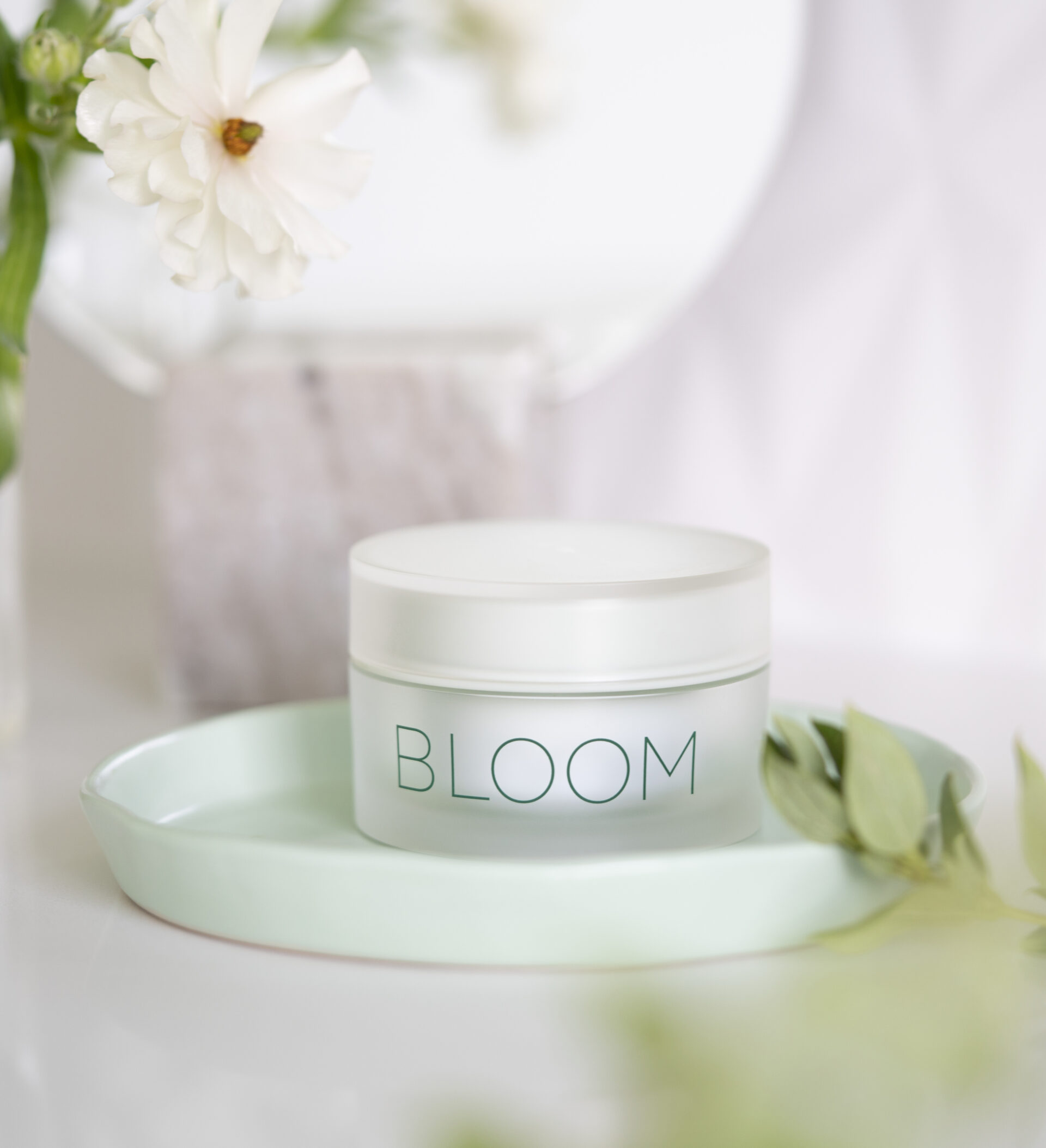 BLOOM Brightening Cream sitting on countertop in a tray with a flower - Young Living Lavender Life Blog 