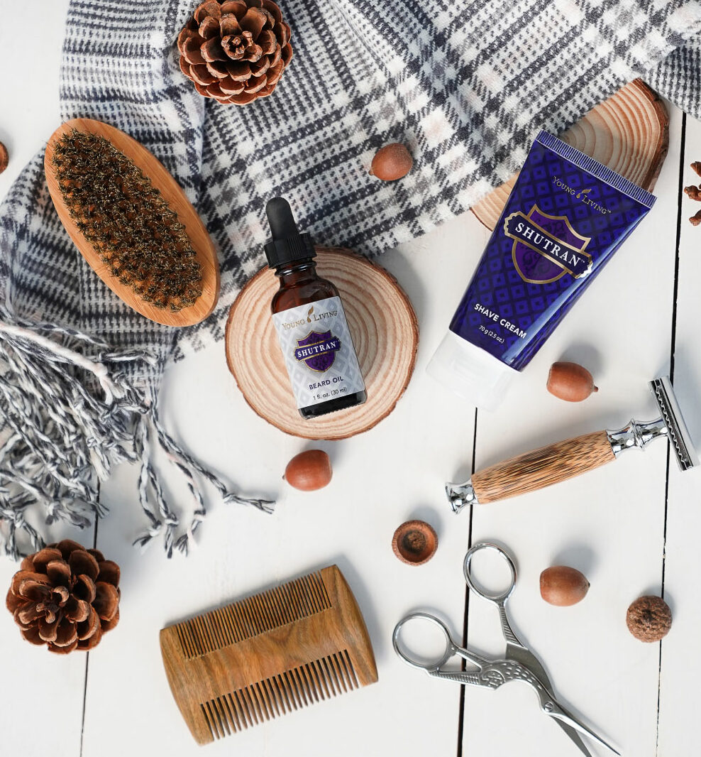 Flat lay of Shutran Beard Oil and Shave Cream alongside men's grooming tools and pine cones - Young Living Lavender Life Blog 
