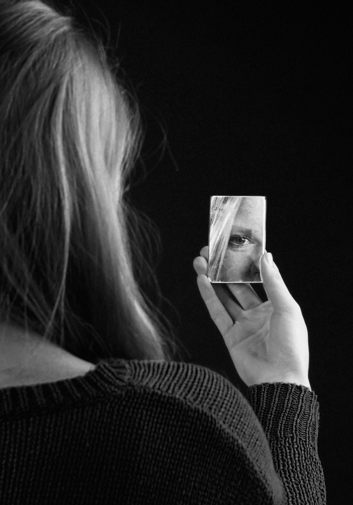 girl staring into a small handheld mirror