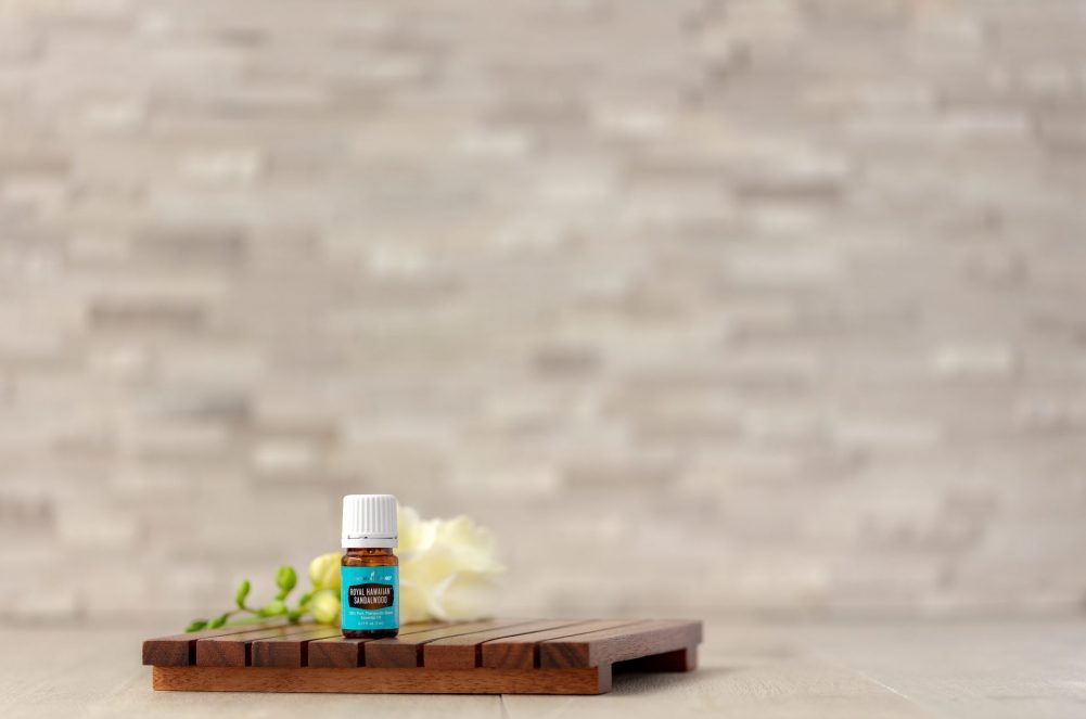 royal hawaiian sandalwood essential oil on a wood platform in front of a tile background
