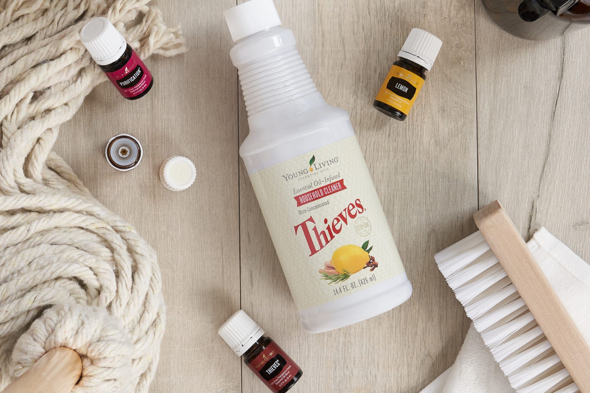 Thieves household cleaner, purification, thieves, aand lemon essential oils surrounded by cleaning supplies