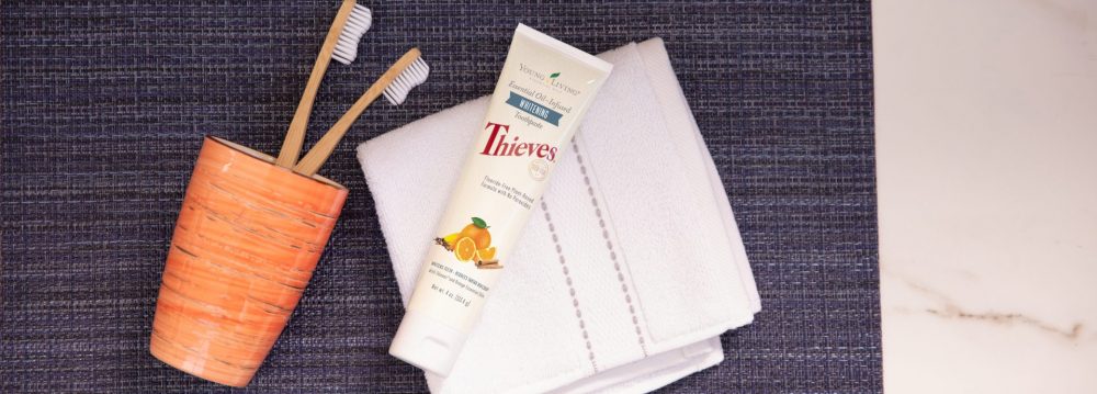 Thieves whitening toothpaste with a tooth brush and washcloth on a counter
