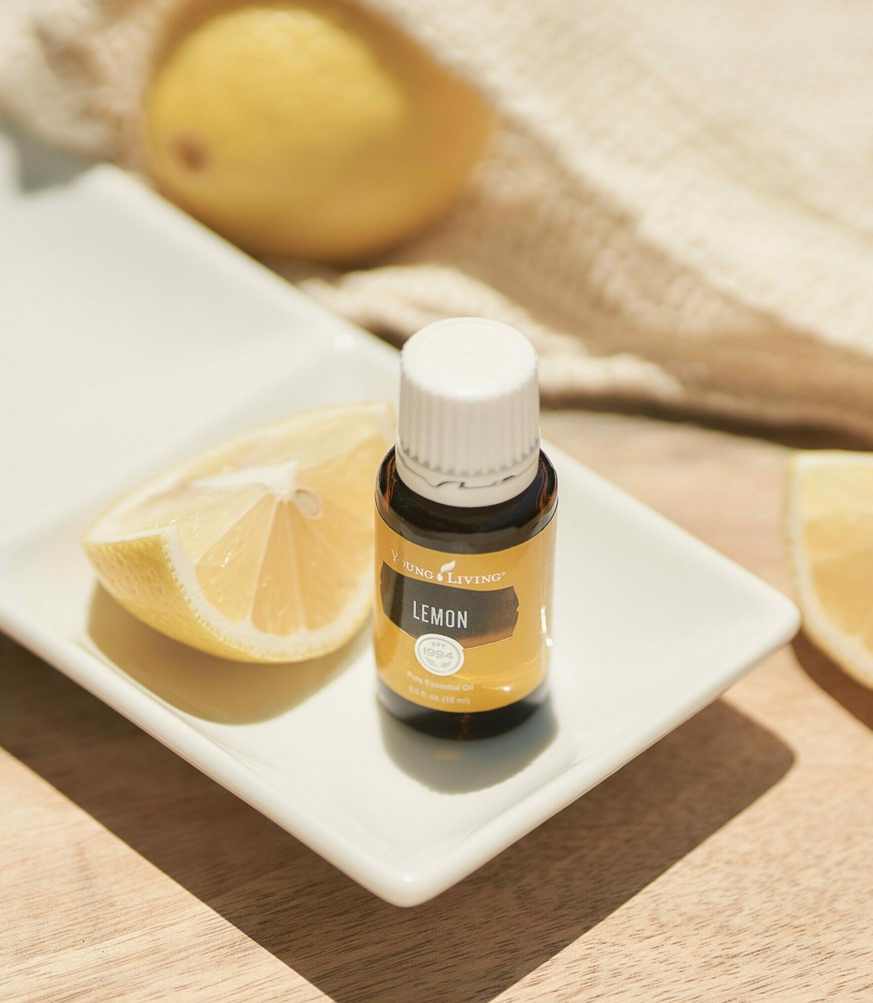 Lemon essential oil sitting on tray with lemon slices - Young Living Lavender Life blog
