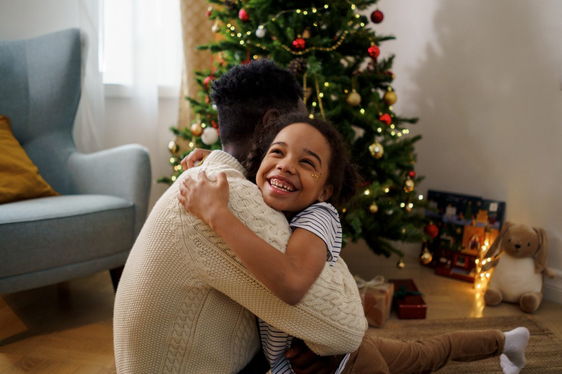 girl hugging parent near the Christmas tree - Young Living Lavender Life Blog 