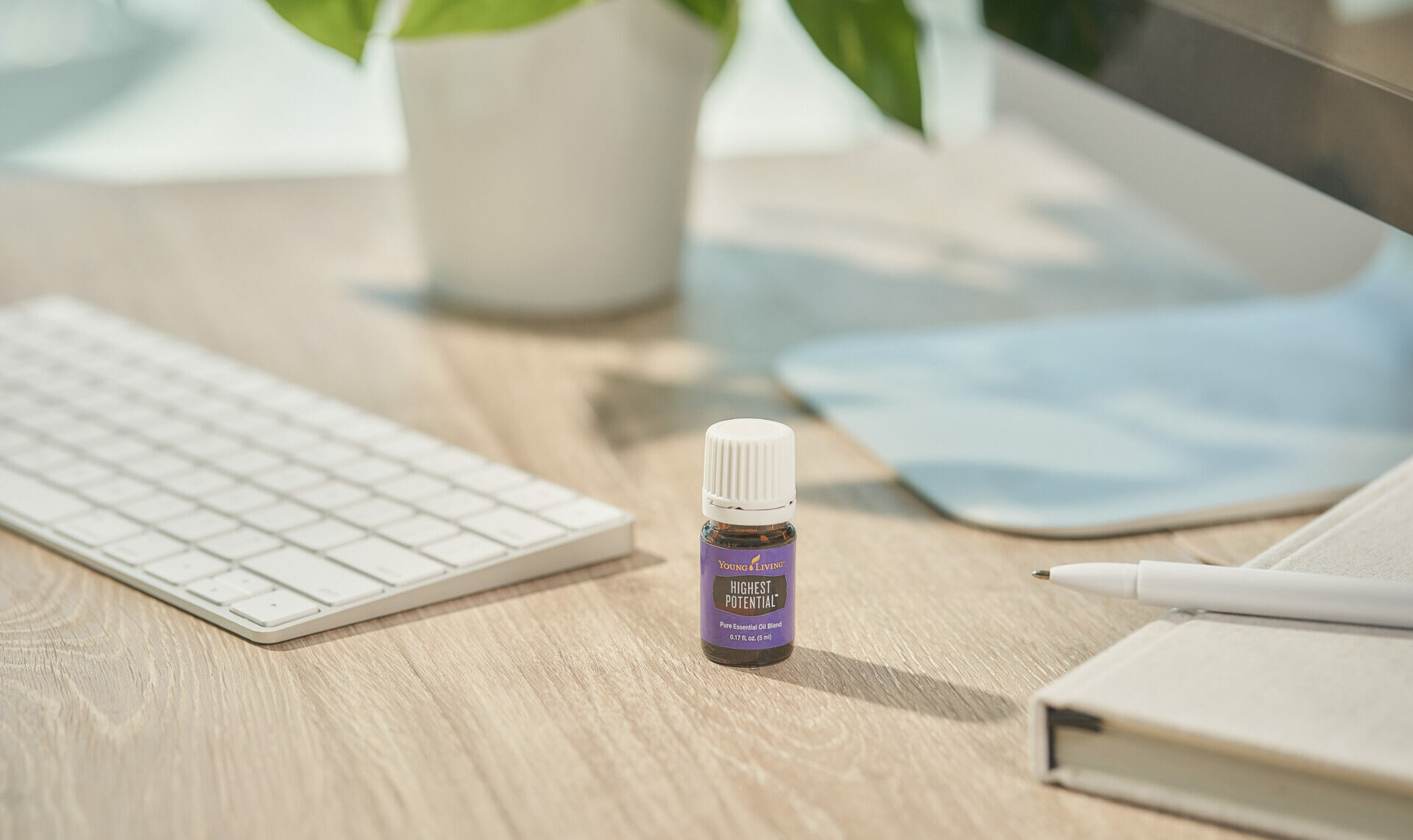 Highest Potential Essential Oil Blend sitting on desk near keyboard and plant - Young Living Lavender Life Blog